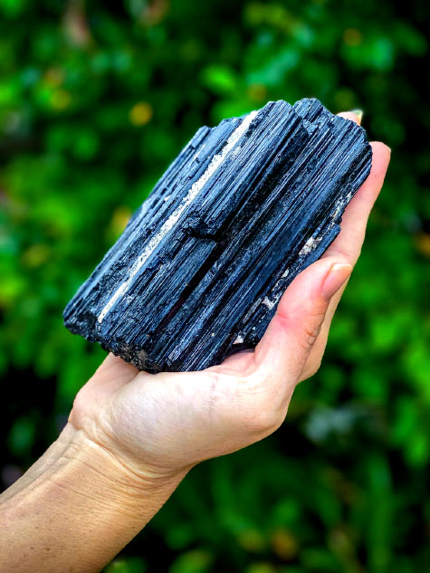 holding a black Tourmaline crystal